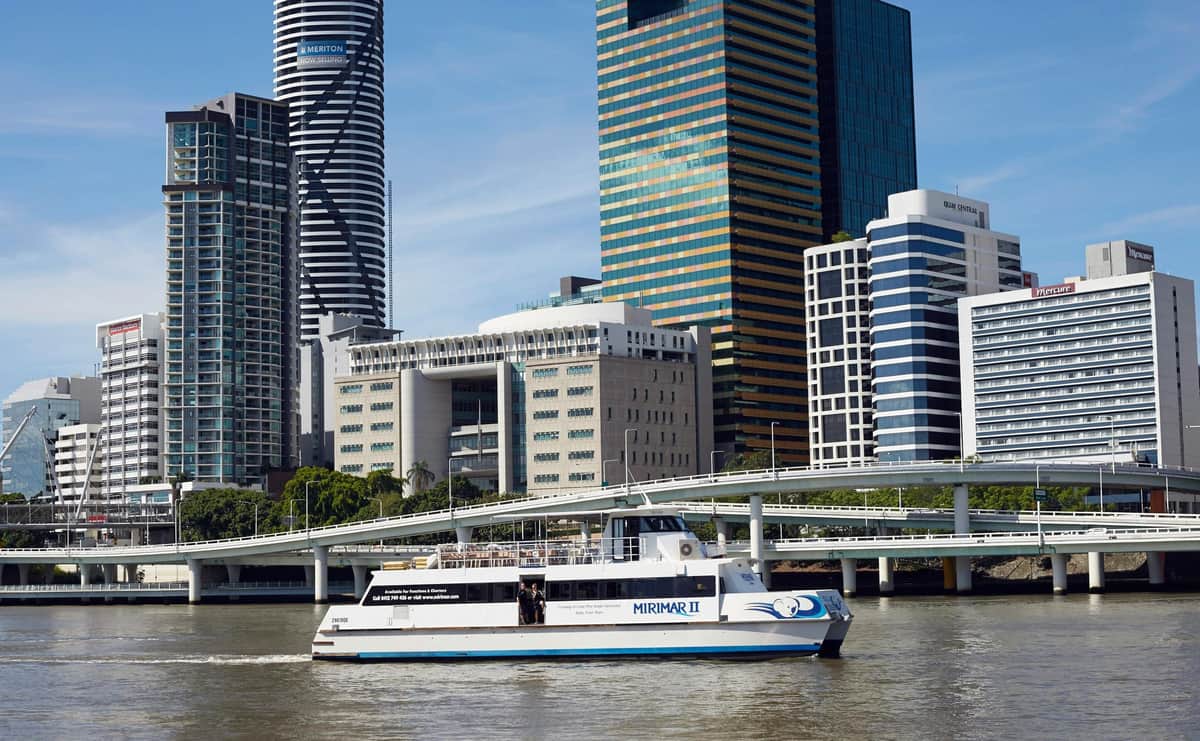 Lone Pine Koala Sanctuary: Entry Ticket + River Cruise from Brisbane A white ferry named "Mirimar II" sails on a river with tall buildings and a bridge in the background on a clear day.