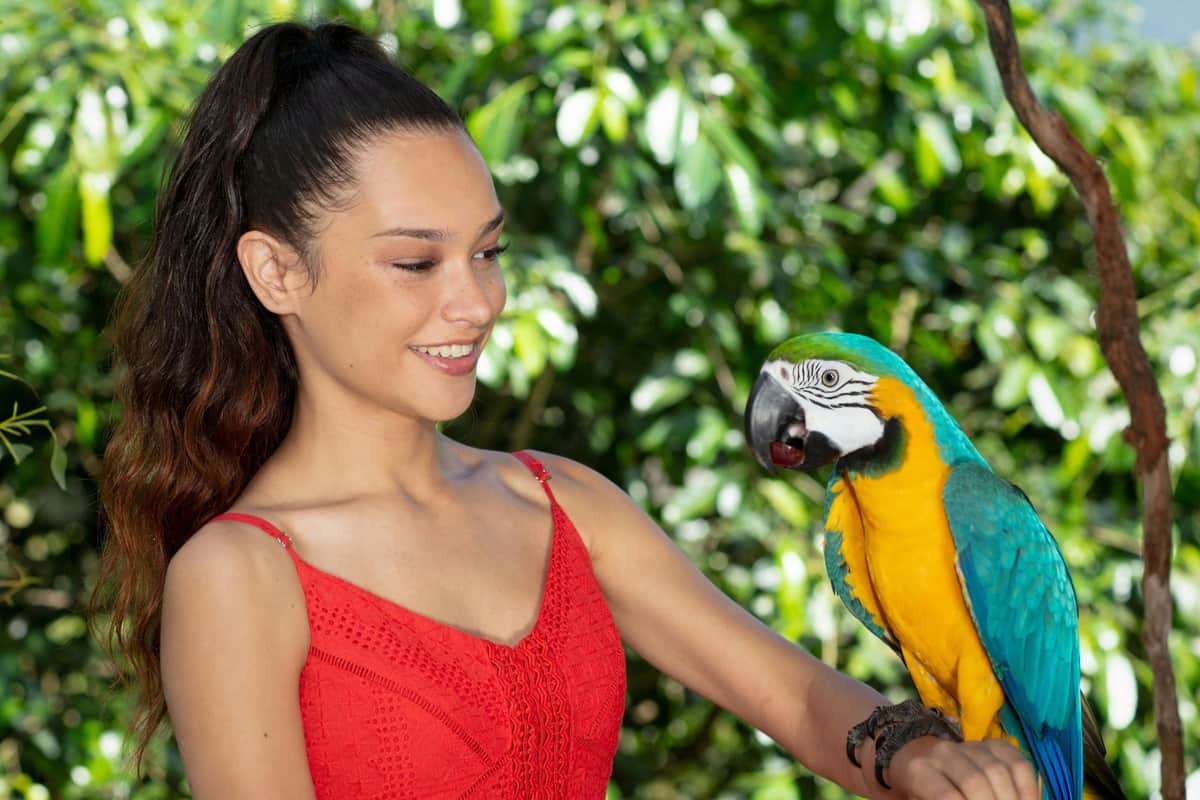 Birdworld Kuranda: Guided Tour A person in a red dress smiles outdoors with green foliage in the background.