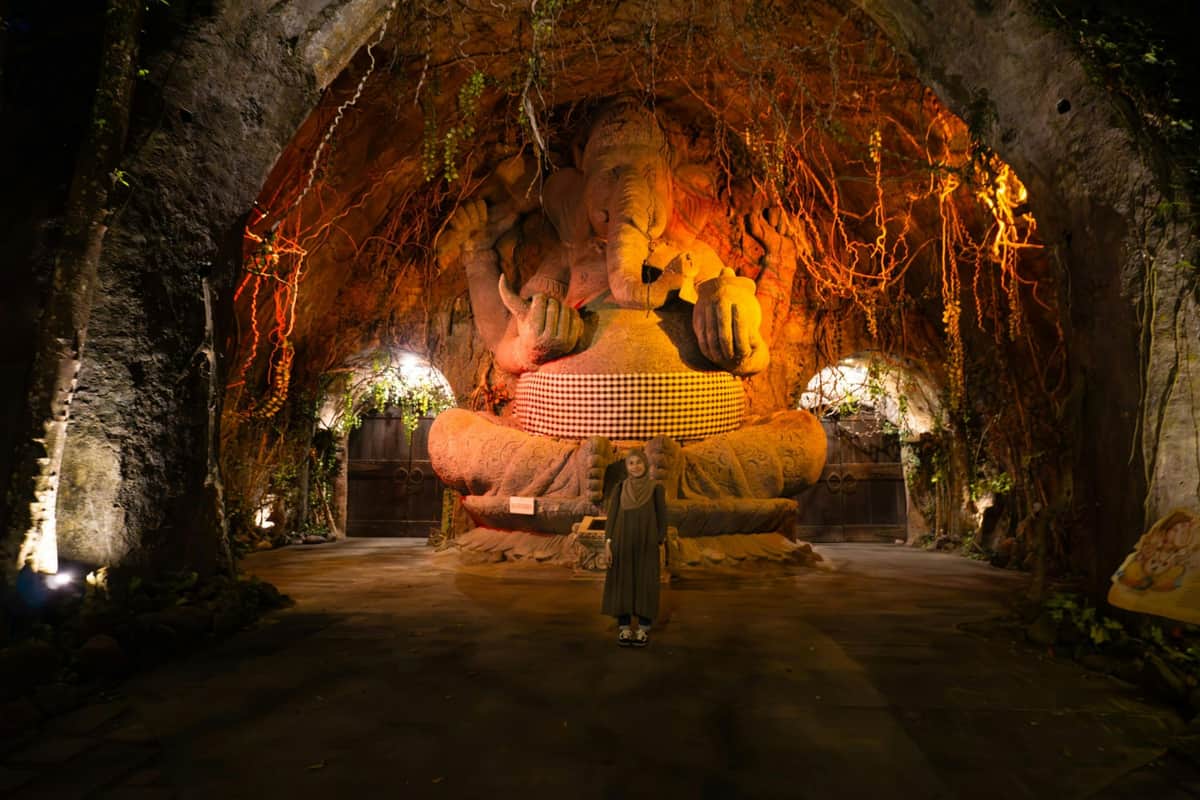 Bali Safari Park: Rhino-arrangement met onbeperkte toegang Iemand die voor een groot, rijkelijk versierd beeld van Ganesha staat in een schemerige, grotachtige omgeving.