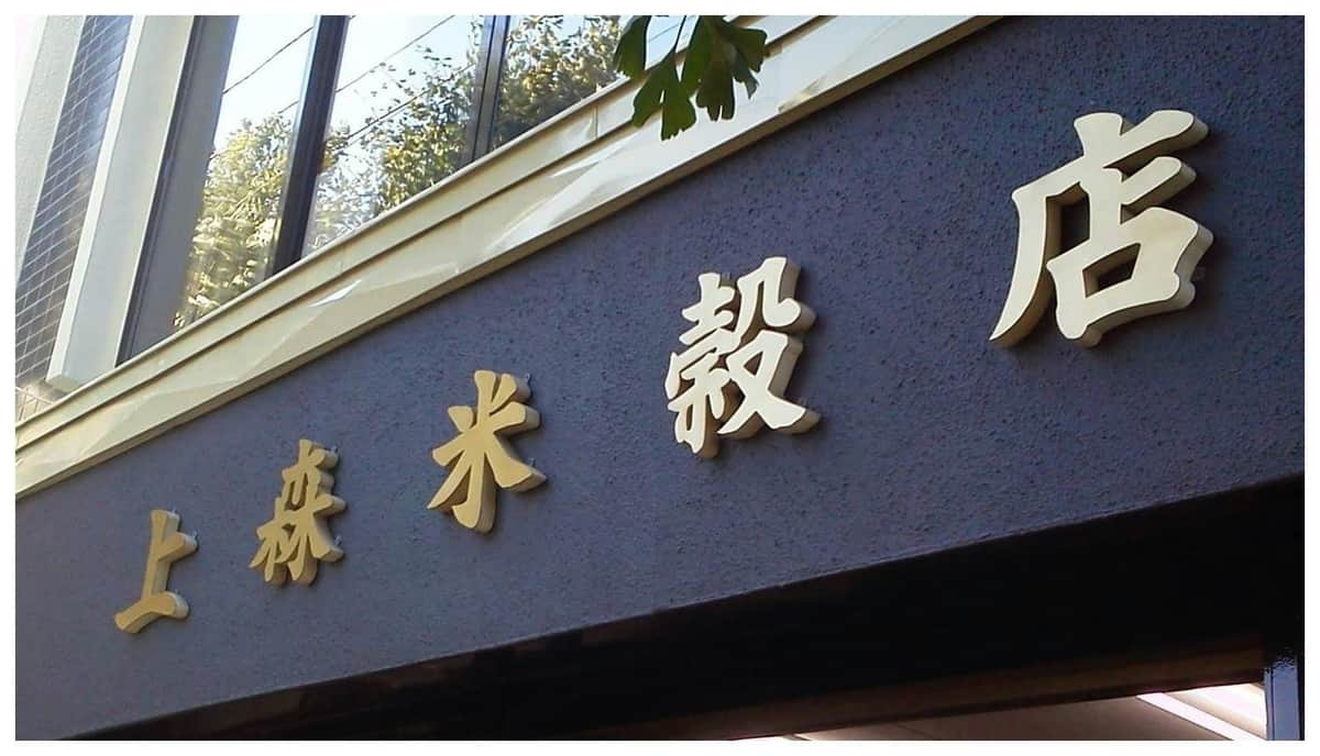 北海道パスをお楽しみください: 1週間無料パス 暗い壁に大きな金色の漢字を貼り付けた建物のファサード。上に葉が見えます。