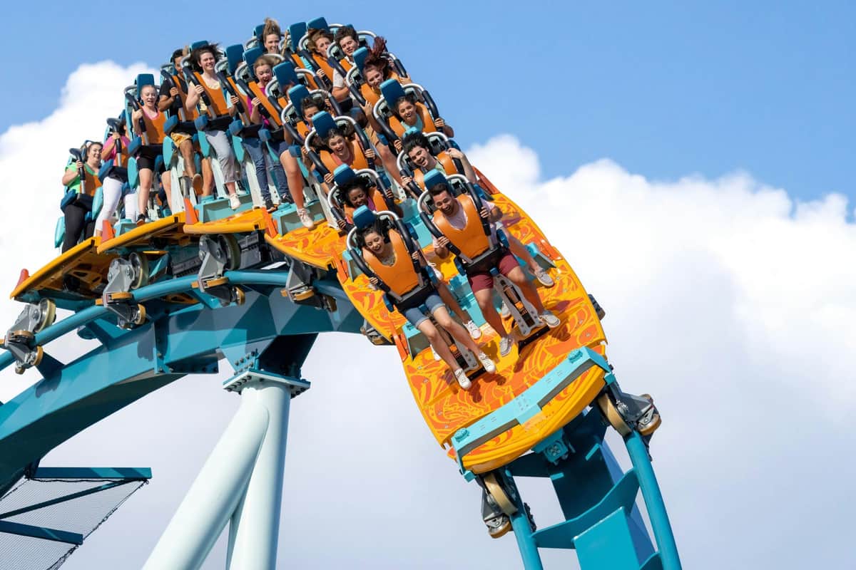 SeaWorld Orlando: Multi-Park Pass + Free All-Day Dining A group of people riding a large rollercoaster, descending a steep drop, all wearing safety harnesses and looking excited.