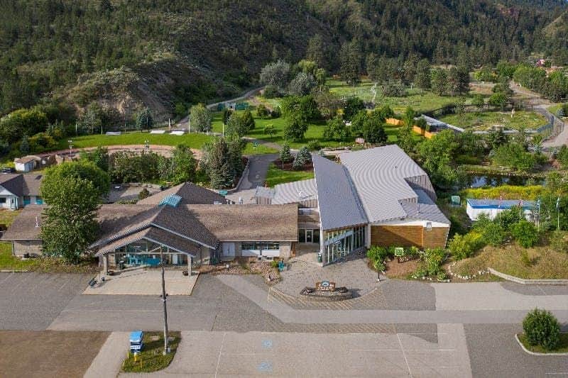 BC Wildlife Park Aerial view of a rural area with buildings, trees, and a mountainous landscape in the background.