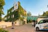 Ingang van de dierentuin van Praag met een gebouw bedekt met groene klimop, een luifelstructuur en bezoekers die in de buurt lopen.